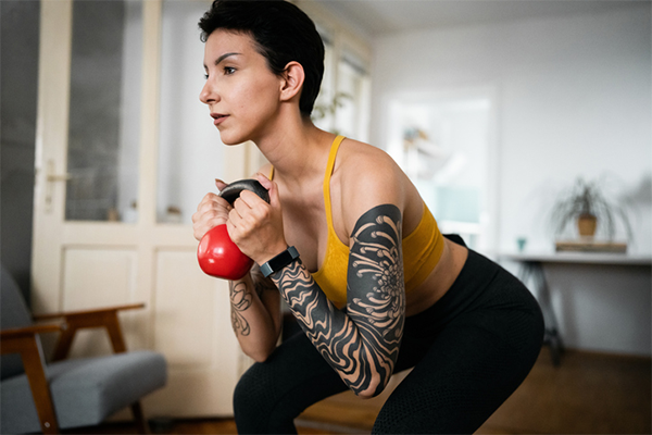 woman doing kettlebell squat | Can You Work Out After Getting a Tattoo